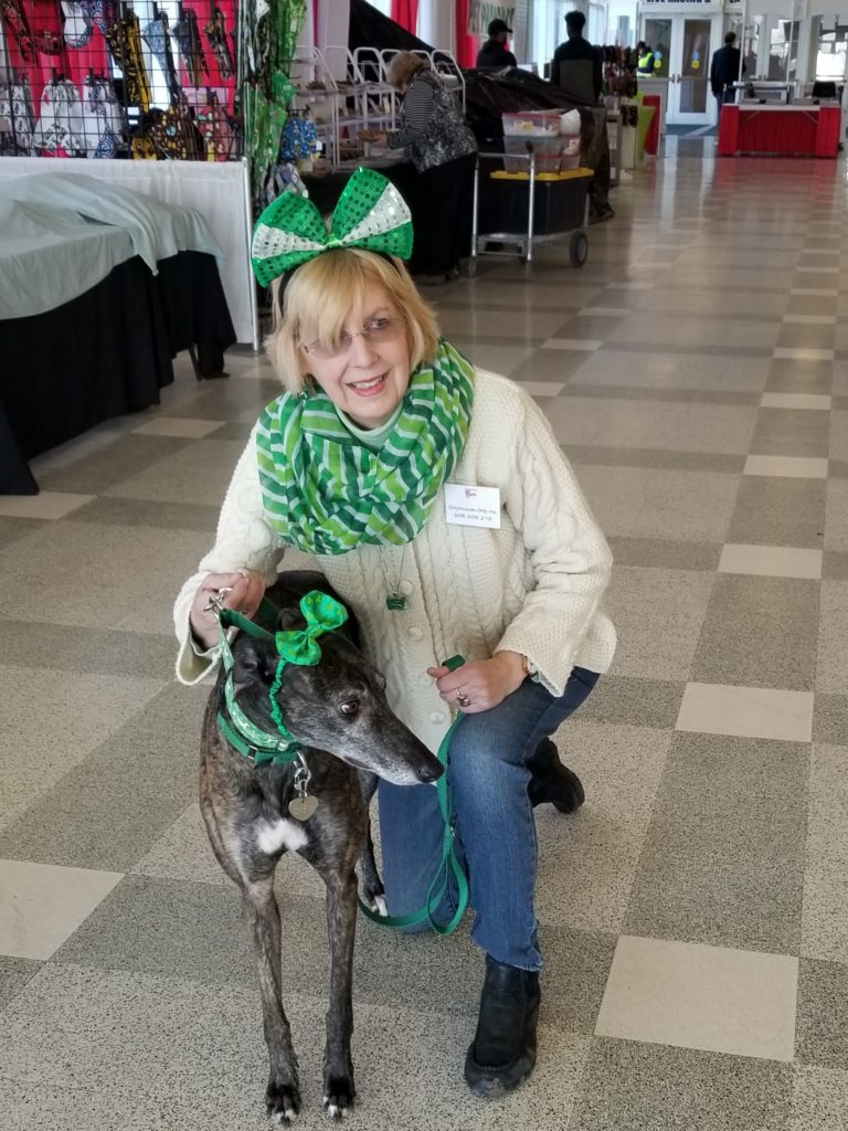 A woman wearing a bow and scarf petting a dog